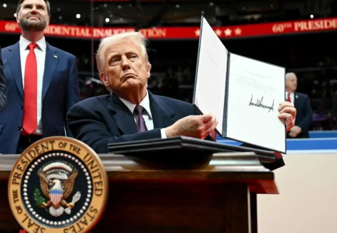 U.S. president displaying a signed executive order related to immigration policies at a formal event